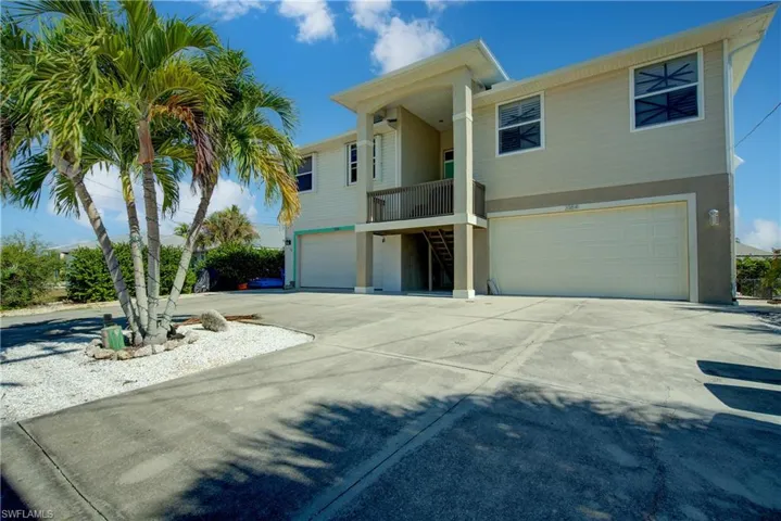 View of front facade featuring stairway, a balcony, concrete driveway, a garage, and stucco siding