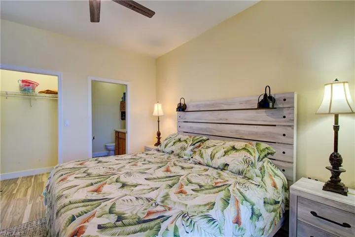 Bedroom featuring wood finished floors, a ceiling fan, and ensuite bath