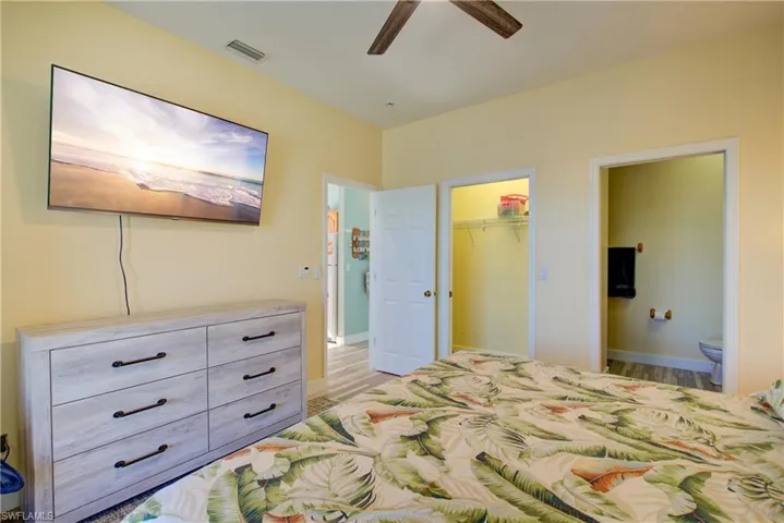 Bedroom with ceiling fan, a walk in closet, light wood-style floors, and ensuite bathroom