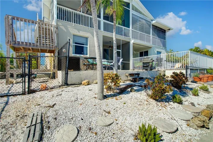 Rear view of house featuring a gate, a balcony, a patio area, a ceiling fan, and stucco siding