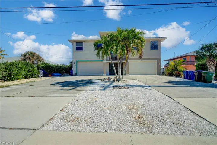 Raised beach house featuring driveway and an attached garage