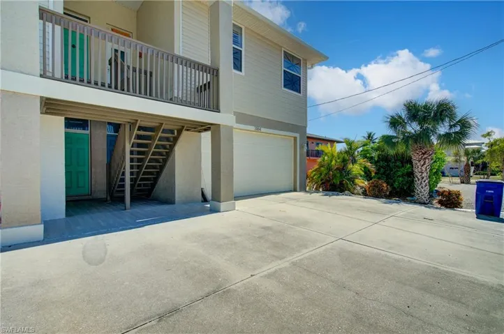 View of home's exterior featuring stairs, a garage, driveway, and stucco siding
