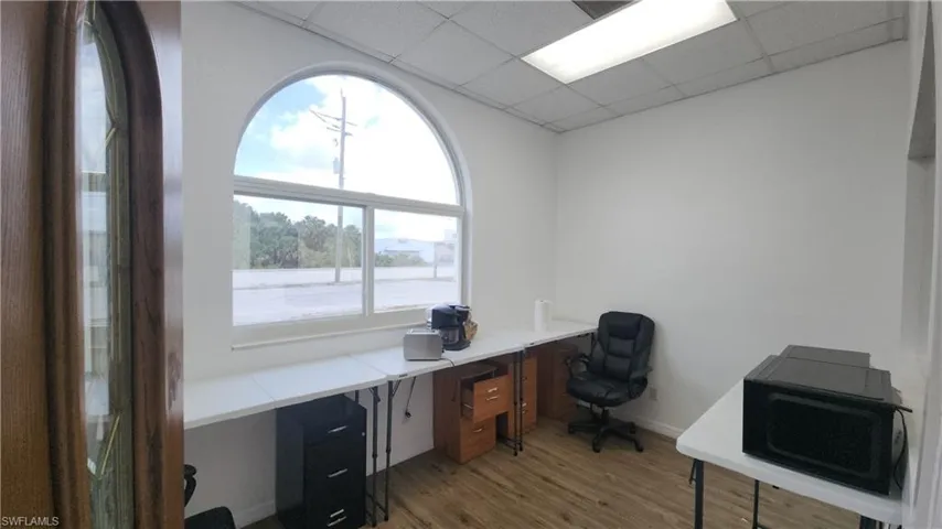 Office with light wood-style floors, healthy amount of natural light, built in desk, and a paneled ceiling