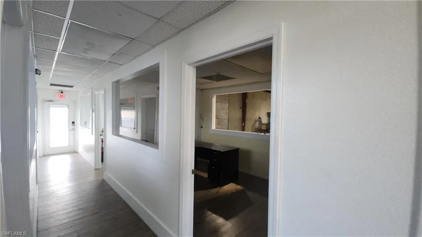 Hall featuring a drop ceiling, wood finished floors, and baseboards