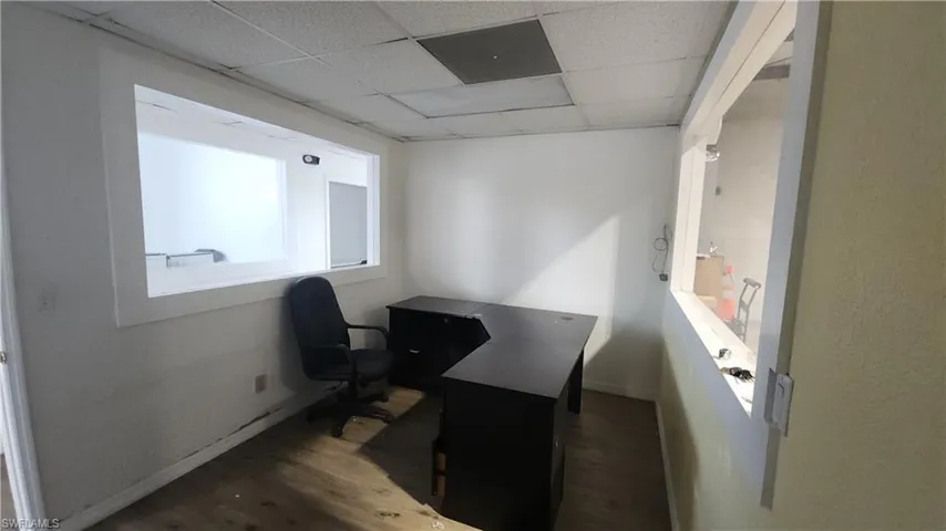 Home office with wood finished floors, a paneled ceiling, and baseboards