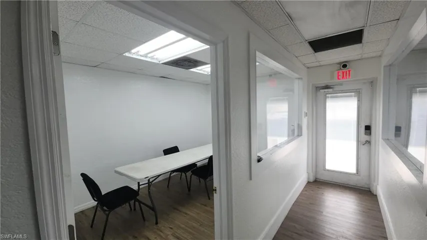 Corridor with a drop ceiling, wood finished floors, and baseboards