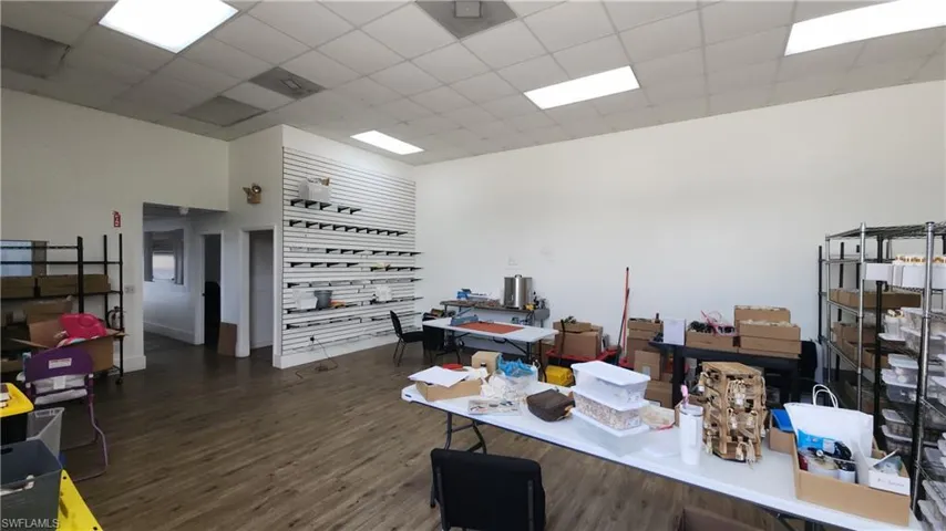 Office area featuring wood finished floors, a drop ceiling, and a high ceiling