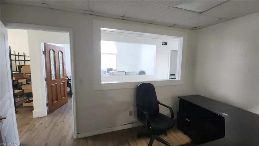 Office area with light wood-type flooring, baseboards, and a drop ceiling