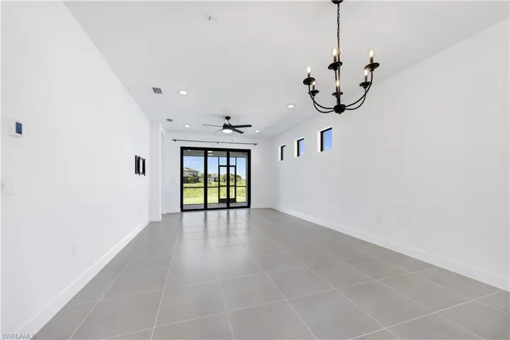 Spacious interior with neutral wall tones, large format tile flooring, and a contemporary black chandelier