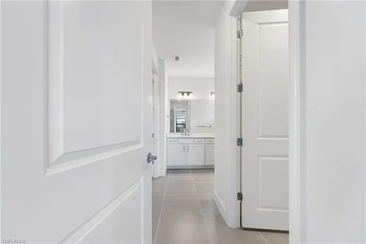 Hallway featuring neutral tile flooring and white paneled doors