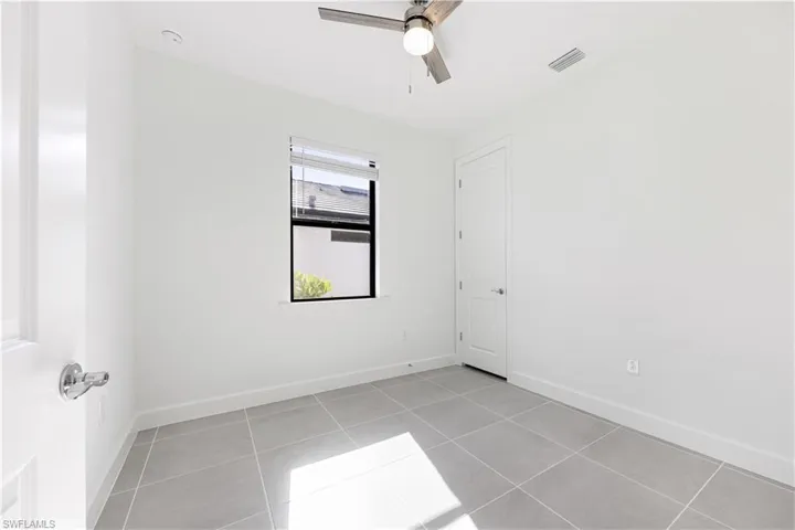 Room with light gray square tile flooring, white baseboards, and white painted walls