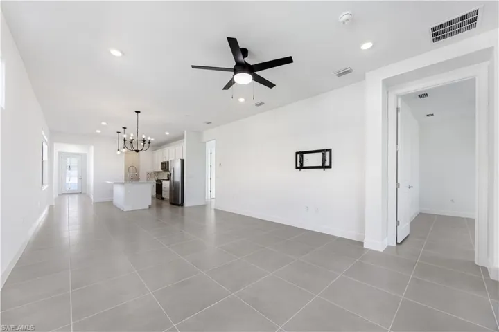 Spacious open-concept living area featuring large format tile flooring, a black ceiling fan, and recessed lighting