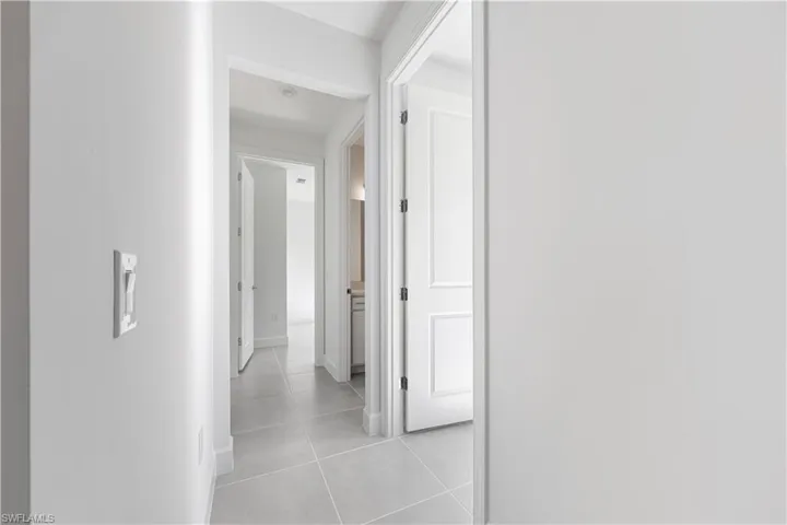 Hallway featuring light gray tile flooring, crisp white walls, and bright white trim