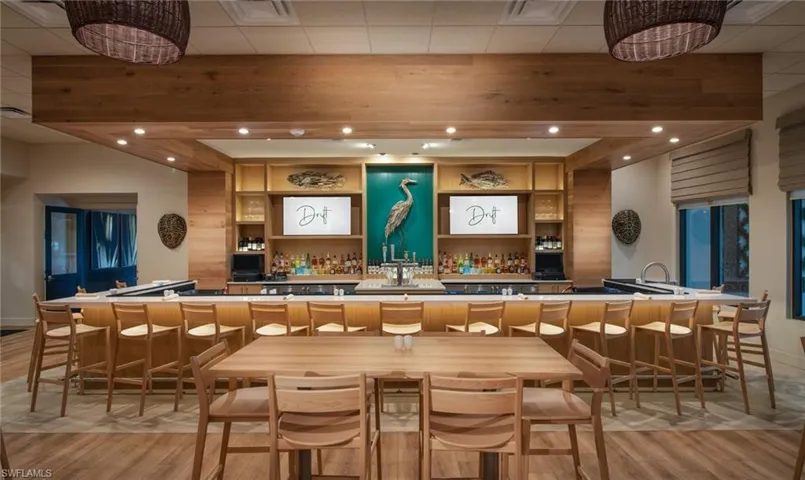 Expansive bar area featuring a wood-finish counter, built-in shelving, wood-finish flooring, and recessed lighting