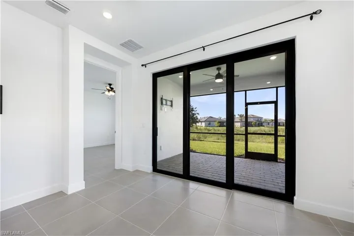 Expansive glass sliding doors with black frames open to a screened patio featuring paver flooring