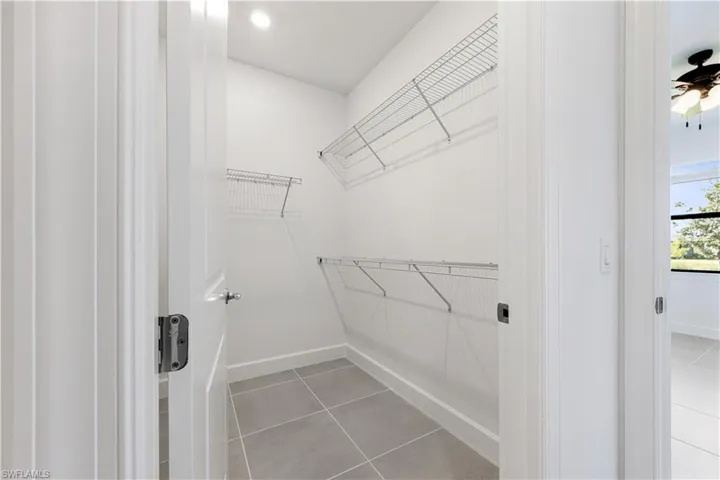 Spacious walk-in closet featuring wire shelving systems, recessed lighting, and large format tile flooring