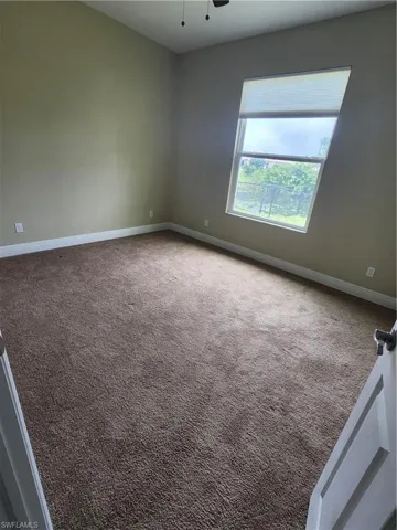 Carpeted empty room featuring baseboards and a ceiling fan