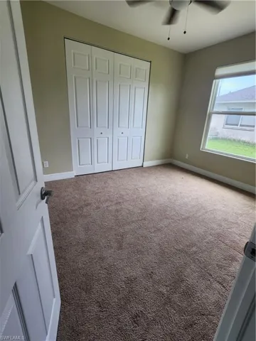 Unfurnished bedroom with carpet, a closet, and ceiling fan