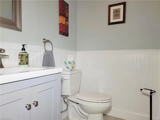 Half bath with wainscoting, toilet, and vanity