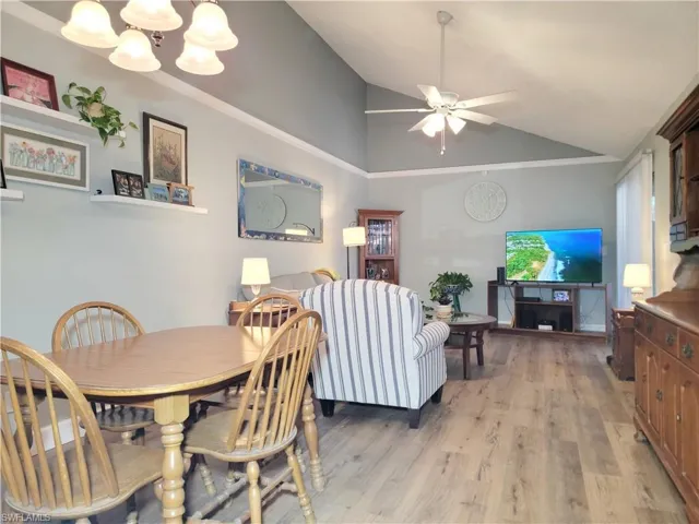Dining area featuring vaulted ceiling, ceiling fan with notable chandelier, and light wood finished floors