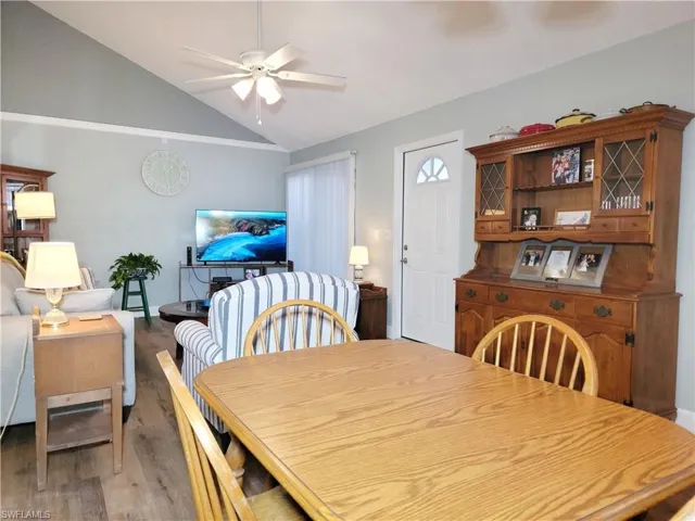 Dining space with light wood-style floors, ceiling fan, and vaulted ceiling