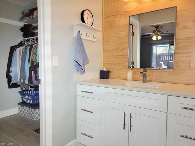 Bathroom with vanity, baseboards, ceiling fan, a spacious closet, and tile patterned floors