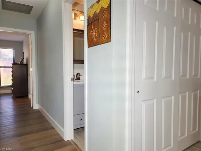 Hall featuring visible vents, baseboards, and dark wood-style floors
