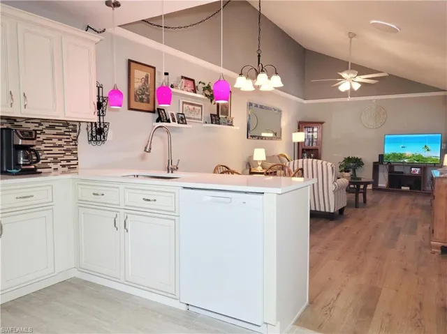 Kitchen with a sink, white cabinets, white dishwasher, ceiling fan, and vaulted ceiling