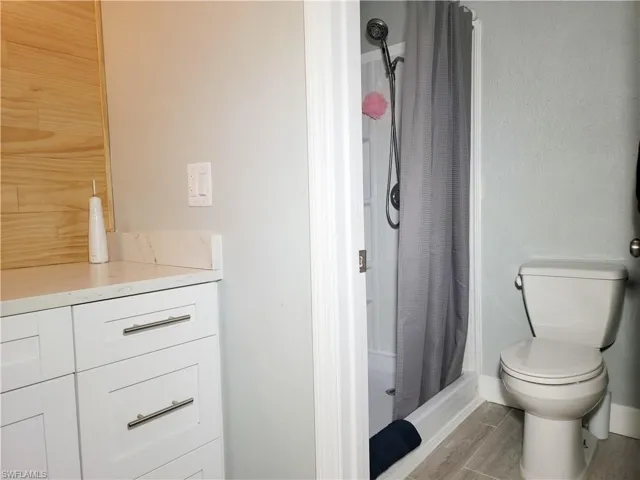 Full bathroom featuring wood tiled floor, toilet, and a shower stall
