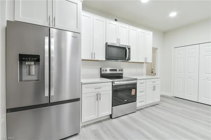 Kitchen featuring appliances with stainless steel finishes, light countertops, white cabinetry, light wood-style flooring, and recessed lighting