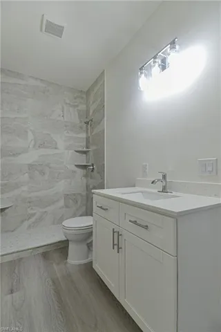Bathroom featuring vanity, a stall shower, and light wood-style flooring