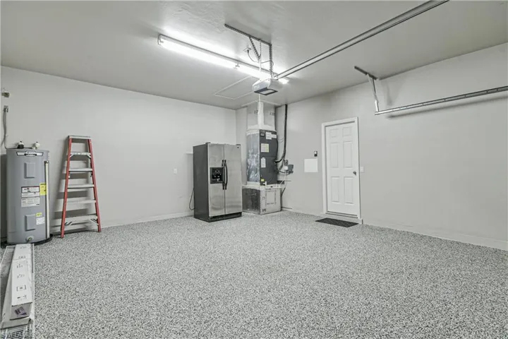 Garage featuring stainless steel refrigerator with ice dispenser, electric water heater, and heating unit