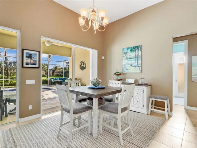 Dining space featuring a chandelier, light tile patterned flooring, a ceiling fan, and a sunroom