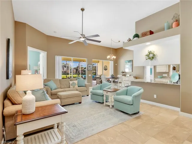 Living area featuring ceiling fan, a chandelier, and a towering ceiling