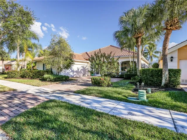 Mediterranean / spanish house with stucco siding, a front lawn, an attached garage, driveway, and a tile roof