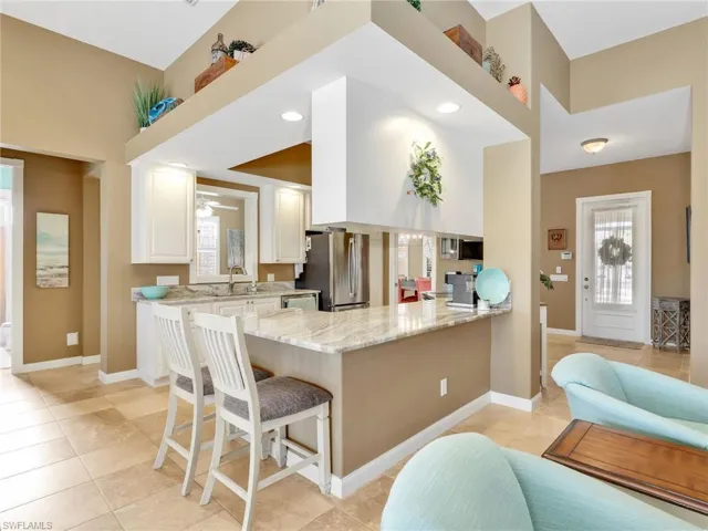 Kitchen with light stone counters, white cabinetry, a peninsula, a breakfast bar area, and appliances with stainless steel finishes