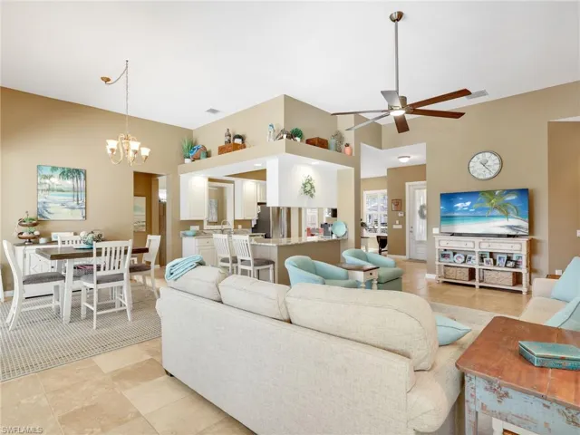 Living area with a high ceiling, light tile patterned flooring, a chandelier, and a ceiling fan