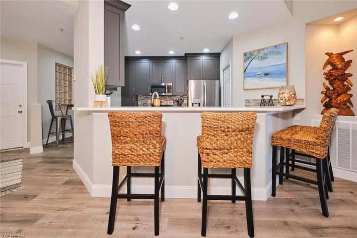 Kitchen with a kitchen breakfast bar, recessed lighting, stainless steel appliances, gray cabinetry, and light wood-style flooring