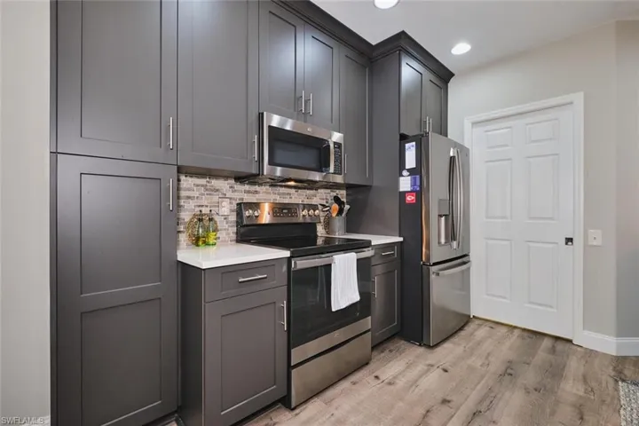 Kitchen featuring stainless steel appliances, light wood finished floors, backsplash, light stone counters, and recessed lighting