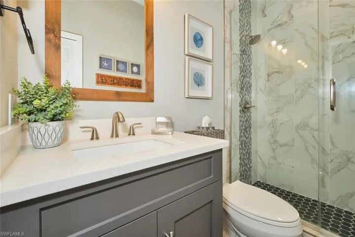 Bathroom with vanity and a marble finish shower