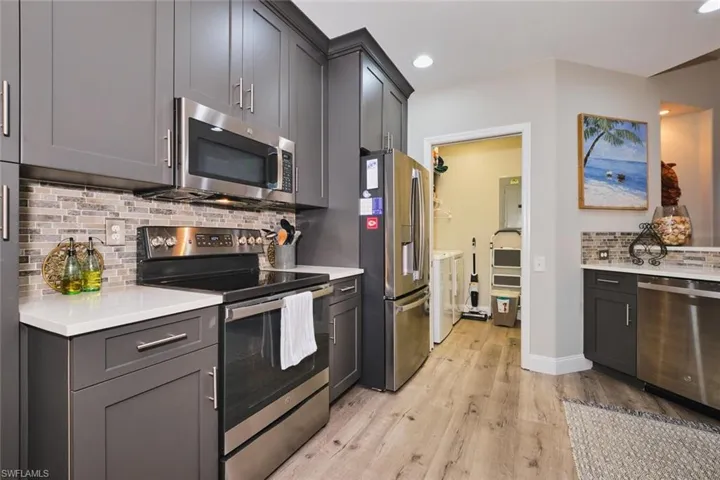 Kitchen featuring stainless steel appliances, decorative backsplash, light stone countertops, gray cabinetry, and recessed lighting