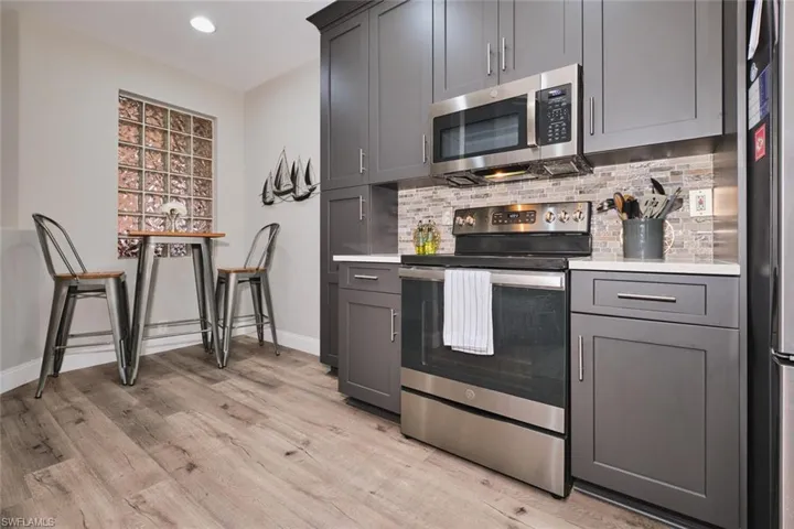 Kitchen with stainless steel appliances, gray cabinetry, light wood finished floors, recessed lighting, and tasteful backsplash