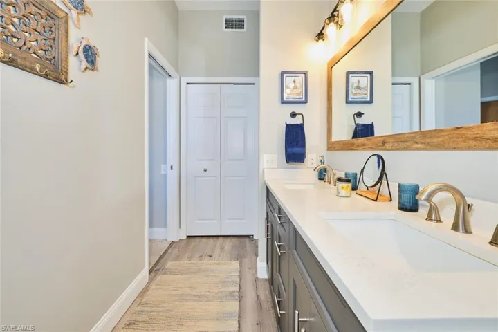 Full bath featuring double vanity, light wood-style floors, and a closet