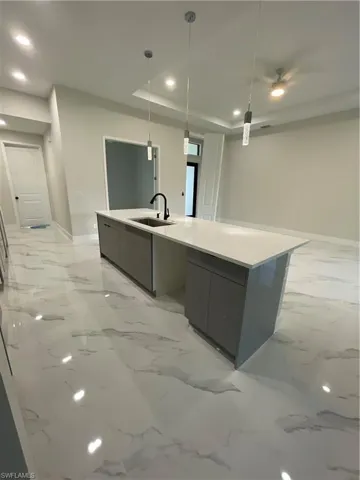 Kitchen with hanging light fixtures, gray cabinetry, sink, a large island
