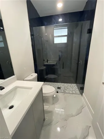 Bathroom featuring a shower with glass door, vanity, and toilet