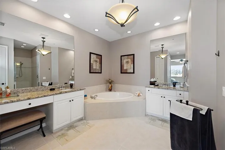 Full bath featuring a shower stall, a bath, two vanities, recessed lighting, and light tile patterned floors