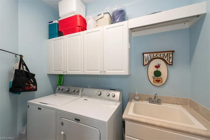 Attached laundry room with washer, dryer and upper cabinets, and sink.