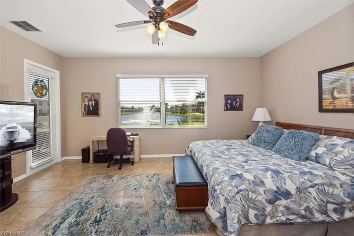 Tiled bedroom featuring ceiling fan, access to exterior, and a desk