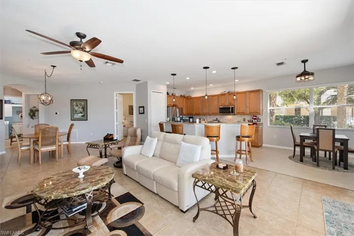 Living area with recessed lighting, arched walkways, light tile patterned floors, a chandelier, and ceiling fan