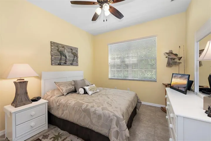 Tiled bedroom featuring ceiling fan and baseboards